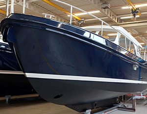 Linssen 30.0 Sedan Amy in der Werft, Backbordseite, blauer Anstrich, vom Boden aus Richtung Bug sehend, beim Teakdeckaufbau