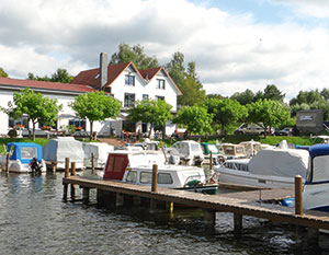 Der Hafen in Mirow mit Anleger im Vordergrund und Restaurant am Ufer 